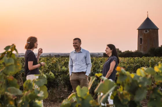 La vigneronne du domaine Ménard-Gaborit discute avec deux visiteurs au milieu des vignes à Monnières près de Clisson