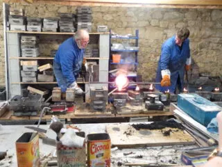 Deux personnes fondant du métal à Sion-les-Mines