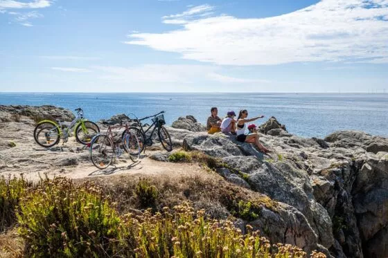 Vélos posés sur les rochers, des cyclistes font une pause en regardant la mer
