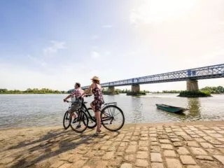 Deux cyclistes à l'arrêt regardent la Loire, à côté d'un pont