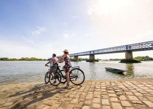 Deux cyclistes à l'arrêt regardent la Loire, à côté d'un pont