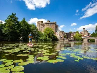 Un château médiéval au bord d'une rivière couverte de nénuphars.