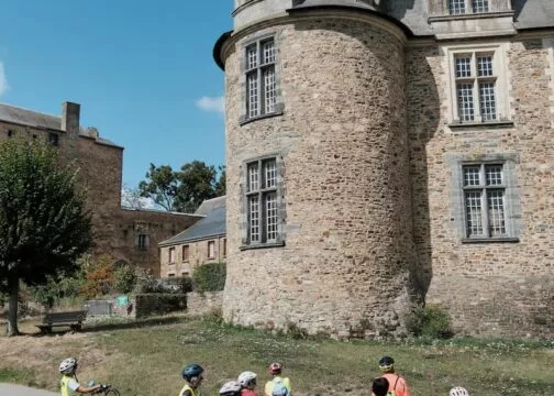 Groupe de cyclistes arrêtés au pied du château de Châteaubriant