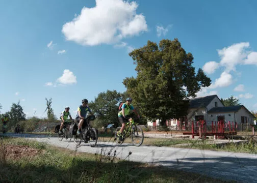 Trois cyclistes en itinérance roulent à côté d'une maison éclusière le long du Canal de Nantes à Brest