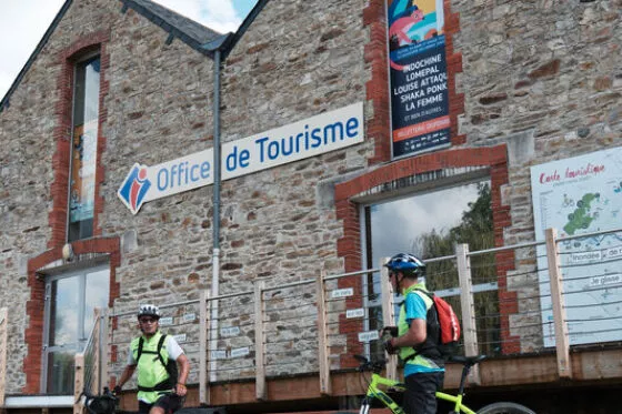 Deux cyclistes à l'arrêt devant un Office de Tourisme