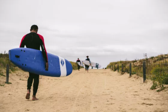 Personne tenant une planche de surf se dirigeant vers la mer