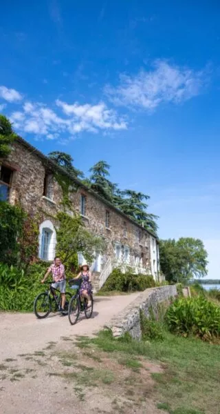 Deux cyclistes arrivent sur une véloroute en bord de Loire. Le ciel est bleu, il fait très beau, c'est l'été.
