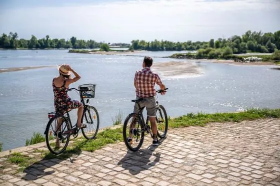 Deux cyclistes font une pause pour regarder la Loire, au soleil