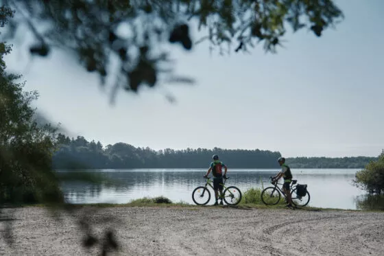 Deux cyclistes en pause sur les bords de l'Erdre avec devant eux une grand étendue d'eau