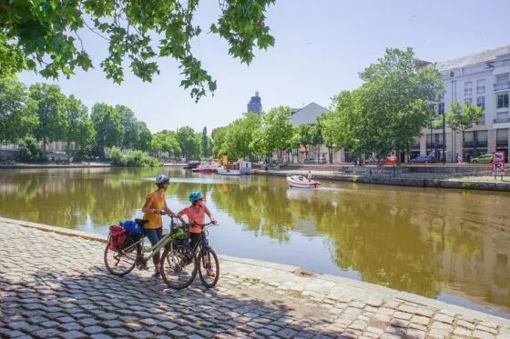 Deux cyclistes sur le bord de l'Erdre à Nantes se reposent à l'ombre d'un arbre