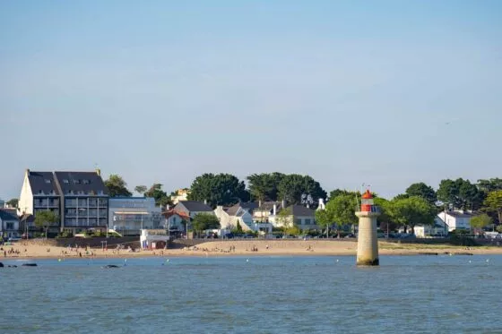 Vue sur une plage entourée d'arbres et d'immeubles, photo prise depuis un bateau au large