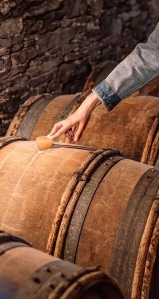 Une guide pose la main sur un tonneau de vin dans une cave du Vignoble