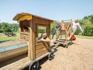 Des grands parents jouent avec leurs petits enfants sur un jeu en bois