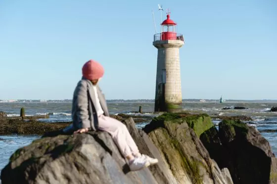 Une petite fille assise sur un rocher regarde vers la mer