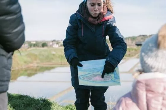 Une guide explique le fonctionnement des marais salants à un groupe de visiteurs