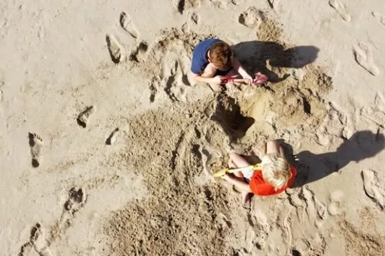 Deux enfants jouent à creuser le sable avec leurs pelles