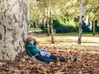 Deux enfants allongés par terre dans les feuilles mortes