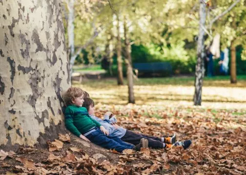 Deux enfants allongés par terre dans les feuilles mortes