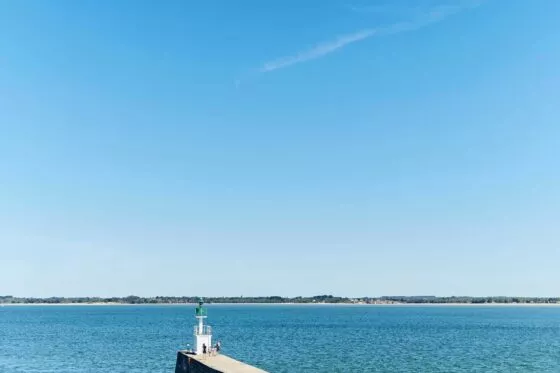 Une jetée serpente de la plage vers la mer bleue