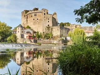 un château médiéval en ruine vu depuis la rive opposée d'une rivière