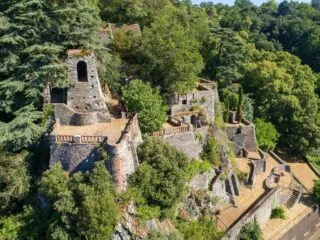 Vue aérienne d'un ensemble de batiments en pierre qui émergent de grands arbres