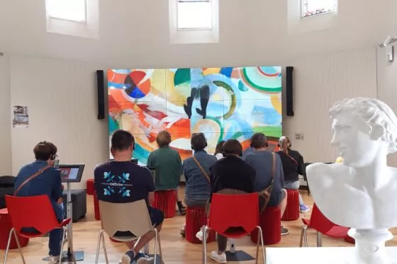 Des enfants admirent une peinture dans une grande salle blanche d'exposition