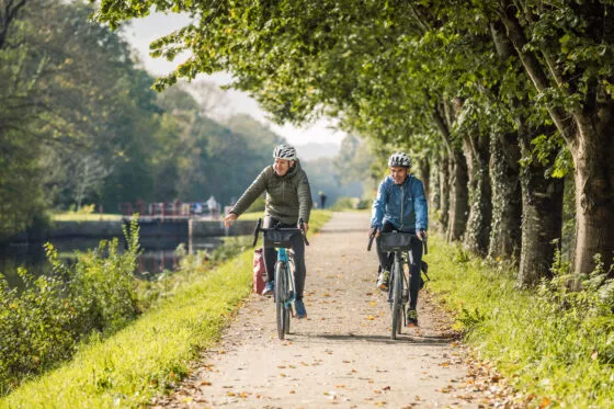 Deux hommes font du vélo en hiver le long du canal de Nantes à Brest, à Blain