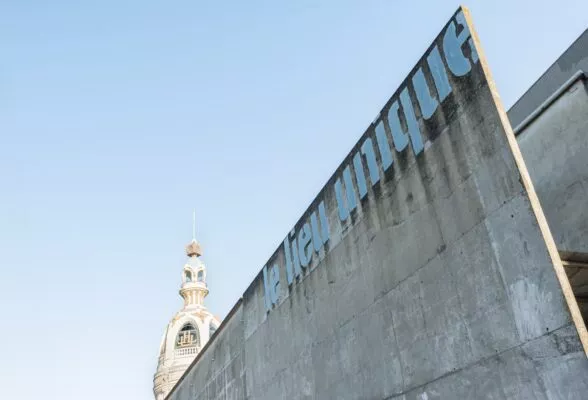 Un grand mur de béton avec l'inscription Lieu Unique et la tour LU dans le fond